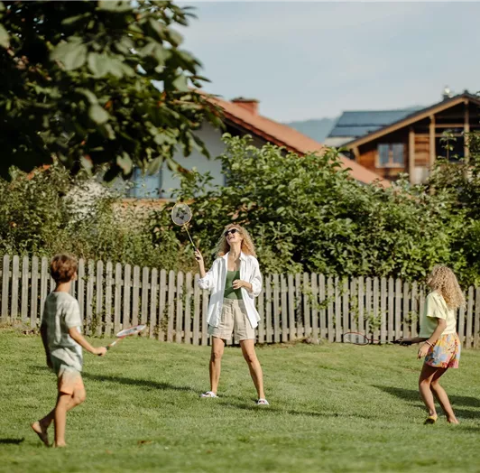 A family is playing in the garden of the Resl Resort. They are having fun playing badminton.