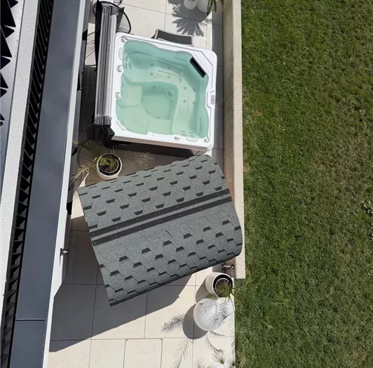 Ein luxuriöser Whirlpool, eine Sauna, ein Pool auf einer sonnigen Terrasse, umgeben von Grünflächen. Neben dem Whirlpool steht ein Sonnenschirm und einige mediterrane Pflanzen.
