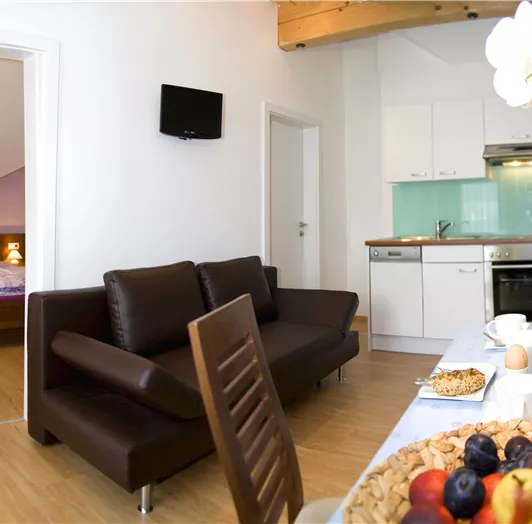 Wohnküche mit Ausziehcouch und Blick in ein Schlafzimmer