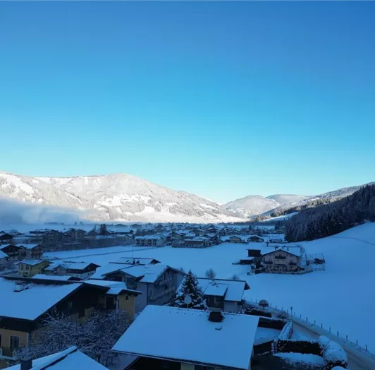 Appartement Weltcupblick mit Ausblick.
Eine Winterlandschaft mit schneebedeckten Dächern und Bergen im Hintergrund.