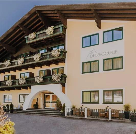 Ein gemütliches Hotel mit einer klassischen Alpenarchitektur. Es hat mehrere Balkone und blühende Fensterkästen.