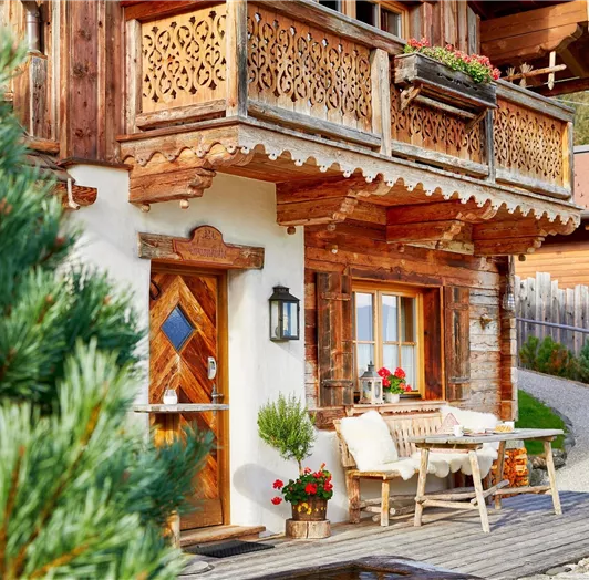 Uriges Chalet mit liebevollen Details und sonniger Terrasse. Die charmante Fassade dieses Chalets vereint traditionelles Handwerk mit alpiner Gemütlichkeit. Auf der sonnigen Terrasse vor dem Eingang laden rustikale Holzmöbel mit Lammfellen zum Verweilen ein. Liebevoll geschnitzte Balkone und naturbelassene Materialien schaffen eine heimelige Atmosphäre – ideal für eine Tasse Kaffee am Morgen oder eine genussvolle Auszeit in den letzten Sonnenstrahlen des Tages.