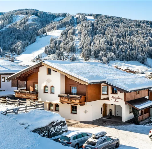 Ein schneebedecktes Alpenhaus in einer malerischen Winterlandschaft. Im Hintergrund sind bewaldete Berge und ein klarer blauer Himmel zu sehen.
Ausblick auf die gegenüberliegende Skipiste Star-Jet-Flachau