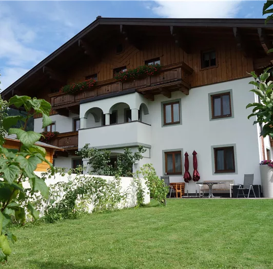 Ein ursprüngliches Haus mit Holzelementen und einem gepflegten Garten. Die Grünfläche ist von Sträuchern umgeben und lädt zum Entspannen ein.