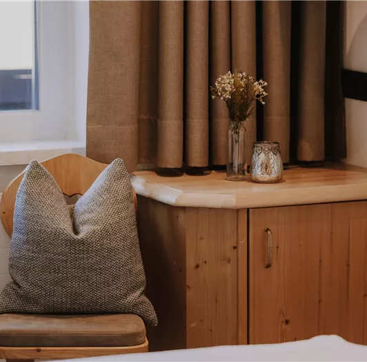 Ein gemütlicher Stuhl mit einem Kissen steht neben einer Holzbank.