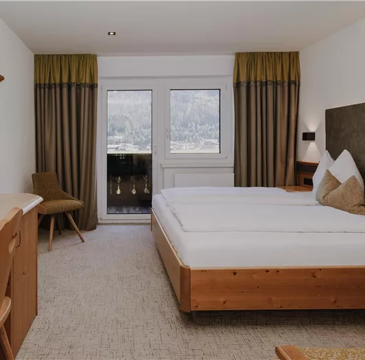 Ein modernes Hotelzimmer mit zwei Betten, einem Schreibtisch und großen Fenstern.