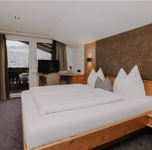 Doppelzimmer Dachgeschoss mit einem gemütlichen Bett und zwei großen Kissen.