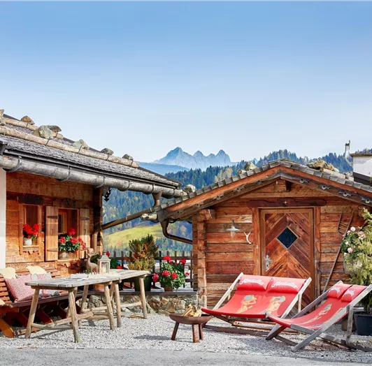 Sonnige Terrasse mit Grillplatz, Lagerfeuerstelle, Panoramablick & Sonos Musiksystem. Diese idyllische Terrasse vereint alpines Flair mit modernem Komfort: Eine gemütliche Sitzecke, rustikale Sonnenliegen und ein Grillplatz laden zum Verweilen ein. Die stimmungsvolle Lagerfeuerstelle sorgt an kühleren Abenden für wohlige Wärme und echte Hüttengaudi. Für die passende musikalische Atmosphäre sorgt das integrierte Sonos Musiksystem, das einfach per App bedient werden kann. Umrahmt von traditionelle