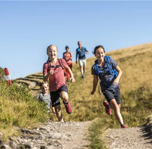 Eine Gruppe von Kindern läuft fröhlich einen Weg im Grünen entlang.