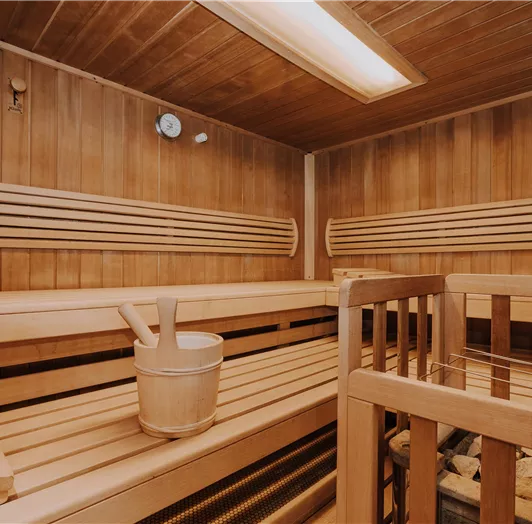 Eine gemütliche Finnische Sauna mit Holzbänken. Die Wände sind aus Holz und schaffen eine entspannende Atmosphäre.