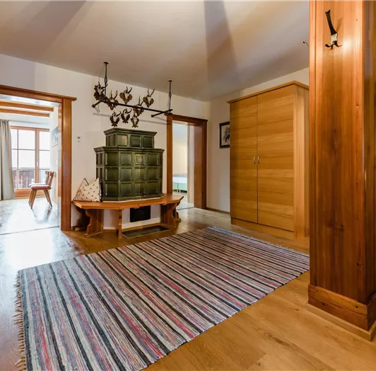 Ein einladender Flur mit Holzfußboden und rustikalen Möbeln. Im Zentrum steht ein Ofen und ein farbenfroher Teppich.