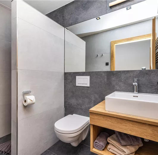Ein modernes Badezimmer mit trendigen Fliesen und einem Waschbecken aus Keramik. Die Einrichtung ist minimalistisch und elegant.