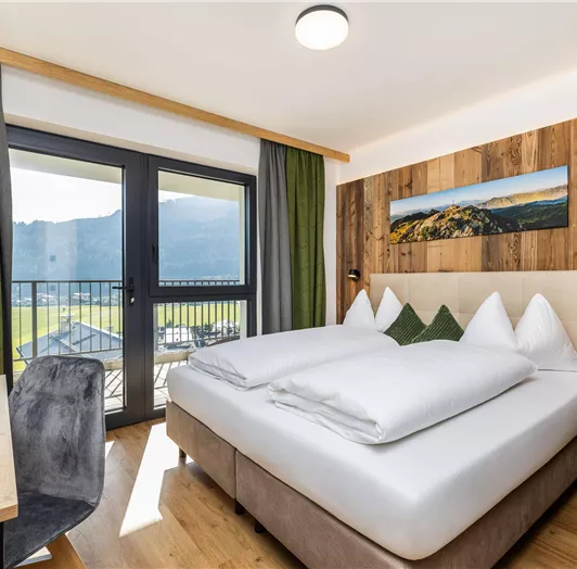 Ein modernes Zimmer mit einem großen Bett und Holzverkleidung. Die Terrasse bietet einen Blick auf die Berge und die Natur.