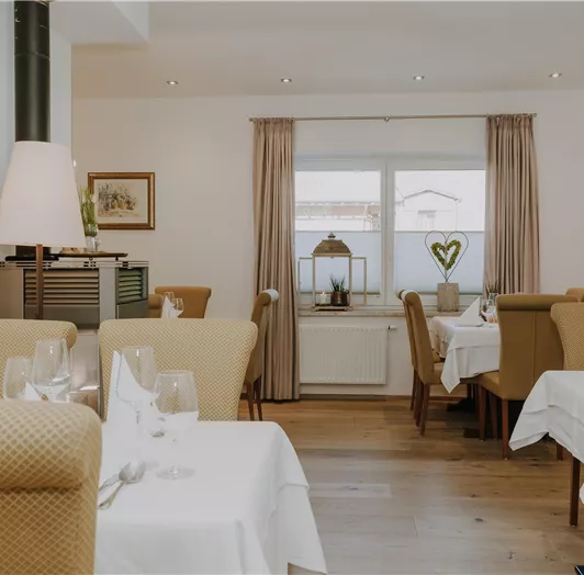 Ein elegantes Restaurant mit beigen Stühlen und weißen Tischdecken.