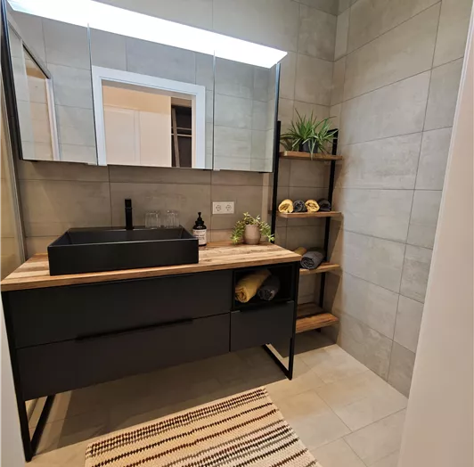 Ein modernes Badezimmer mit einem eleganten Waschbecken und viel Stauraum. Die Wände sind mit fliesen in neutralen Tönen dekoriert.