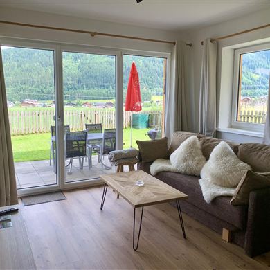 Naturkino direkt vor der Tür. Große Fensterfronten und direkter Zugang zur Terrasse eröffnen einen traumhaften Panoramablick auf die umliegende Bergwelt. Vom gemütlichen Wohnbereich aus schweift der Blick über grüne Wiesen und Wälder – ein Anblick, der zu jeder Jahreszeit begeistert. Die Kombination aus hochwertigem Interieur und beeindruckender Aussicht macht dieses Appartement zum Rückzugsort mit echter Wohlfühlgarantie.
