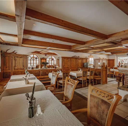 A cozy restaurant & breakfast room with wooden furniture. The tables are set and the light is warm and inviting.
