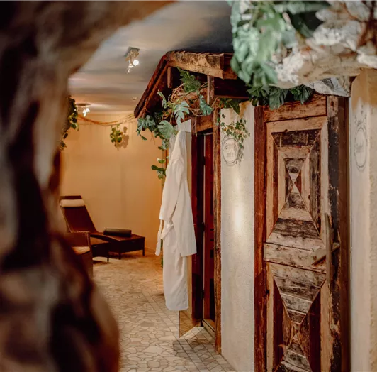 A relaxing wellness area with rustic wooden doors and soft lighting.  
Plants decorate the space and create a calming atmosphere.