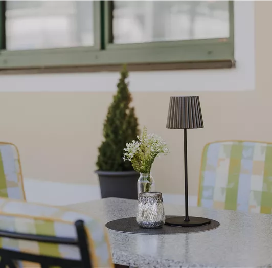 Ein schöner Tisch im Freien mit bunten Stühlen und einer modernen Lampe.