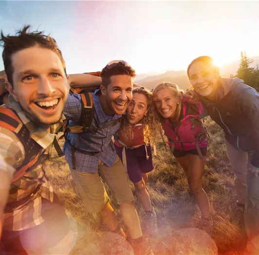 Eine Gruppe von fünf Freunden macht ein fröhliches Selfie in der Natur.