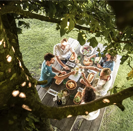 Eine Gruppe von Freunden sitzt an einem Tisch im Freien und genießt ihr Essen.