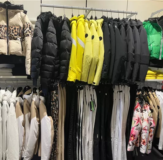 Eine Auswahl an Winterjacken in verschiedenen Farben hängt an einem Kleiderständer. Damen Abteilung