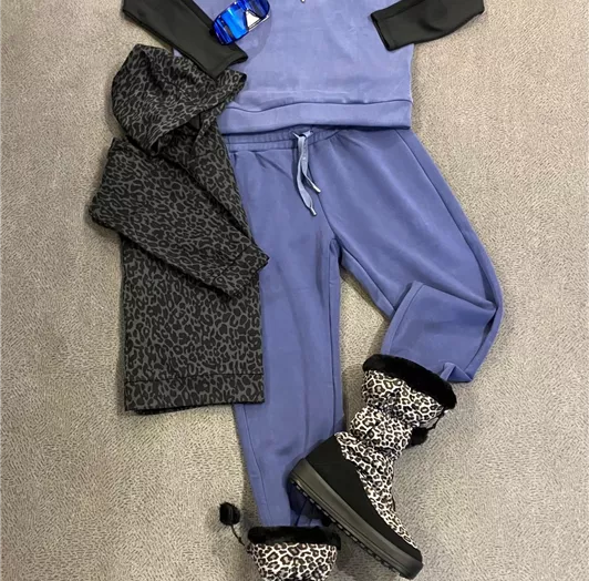 Ein lässiges Outfit bestehend aus einem blauen Hoodie, einer grauen Jacke und passenden Jogginghosen. Ergänzt wird das Ensemble durch stylische Stiefel mit Leoparden-Muster.