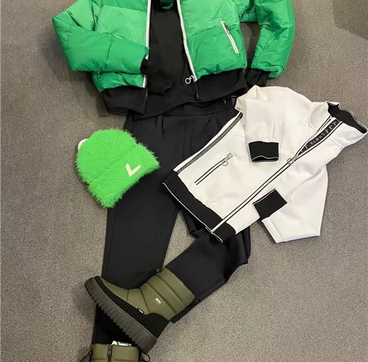 Ein modernes Outfit bestehend aus einer grünen Jacke, einer weißen Jacke, einer schwarzen Hose und stylischen Stiefeln. Dazu gehört eine grüne Mütze für den sportlichen Look.