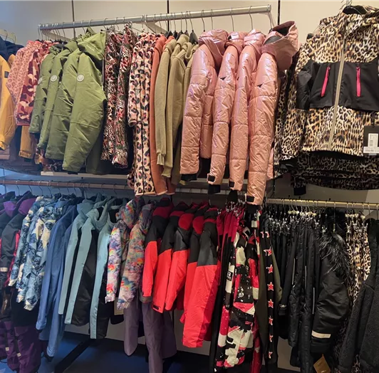 Eine Auswahl an bunten Jacken hängt in einem Geschäft. Die Kollektion umfasst verschiedene Farben und Muster.
Kids-Girl