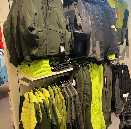 Eine Auswahl an funktioneller Outdoor-Bekleidung in verschiedenen Farben, darunter Jacken und Hosen. Männer Abteilung