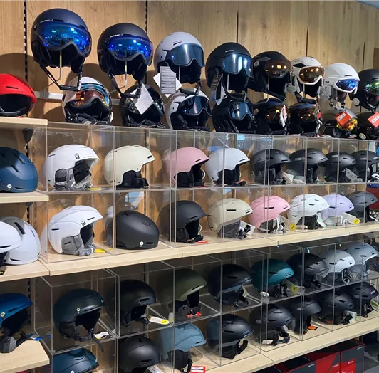 Ein Regal mit verschiedenen Skihelmen in unterschiedlichen Farben und Designs. 
Sport Perner Ski Helmet