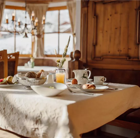 A beautifully set table with breakfast, including fresh bread, fruit, and a drink. This is how the holiday morning begins at the Bed and Breakfast Hotel Lisa in Flachau.