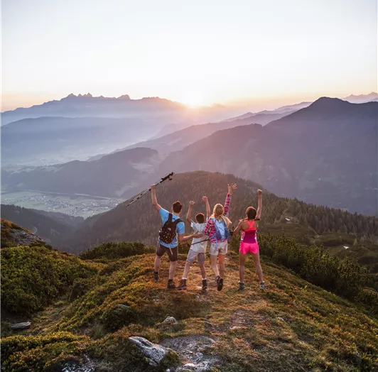 Vier Menschen stehen auf einem Hügel und blicken in die Ferne.