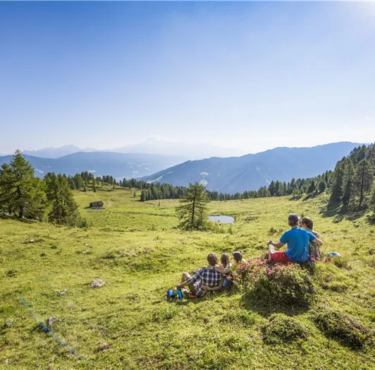 Eine Gruppe von Menschen sitzt auf einer Wiese und genießt die Aussicht auf die Berge.