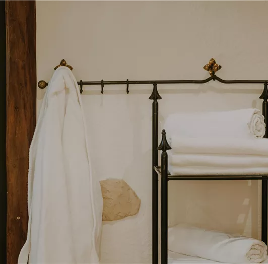 Ein Wellnessbereich mit einem Handtuchhalter und einem Regal voller frischer, stapelbarer Handtücher.