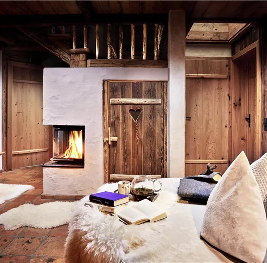 Urlaub im Chalet – Ihr Rückzugsort in den Bergen. Entfliehen Sie dem Alltag und genießen Sie unvergessliche Tage in unserem liebevoll eingerichteten Chalet. Knisterndes Feuer im Kamin, natürliche Materialien aus Holz und Stein sowie kuschelige Felle schaffen eine warme Wohlfühlatmosphäre. Lassen Sie sich in weiche Kissen sinken, lesen Sie ein gutes Buch oder genießen Sie eine Tasse Tee bei flackerndem Kaminlicht. Ob romantische Auszeit zu zweit, erholsamer Wellnessurlaub oder gemütliches Beisamm